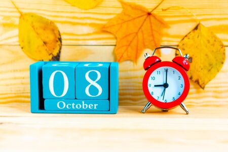 October the 8th. Blue cube calendar with month and date and alarm clock on wooden background.の写真素材