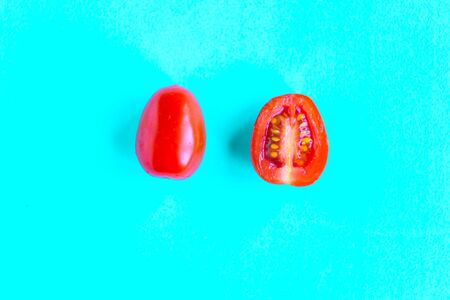 Sliced fresh cherry tomato on blue background, minimal concept, summer time conceptの写真素材