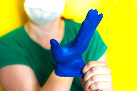 girl in a medical mask puts on gloves, covid-19 conceptの写真素材