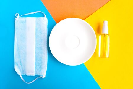 Antiseptic, medical mask and empty plate on color background. Minimal concept. Covid-19 conceptの写真素材