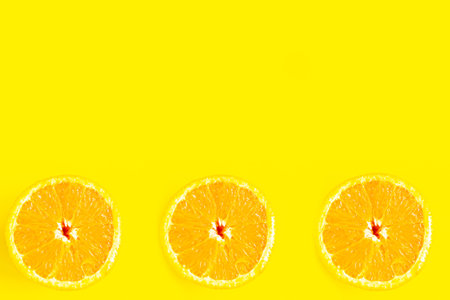 Sliced fresh sweet oranges on bright yellow background, minimal concept, copy space for the text,...