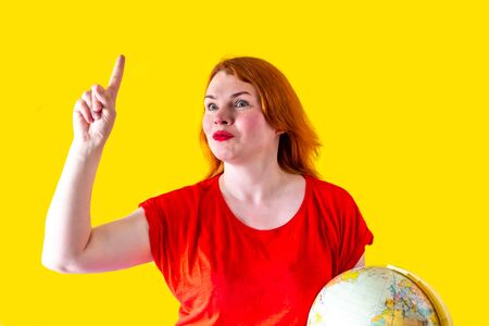 Portrait of beautiful redhead girl with globe on yellow background, travel conceptの写真素材