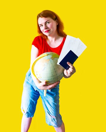 Portrait of beautiful redhead girl with globe and documents on yellow background, travel conceptの写真素材