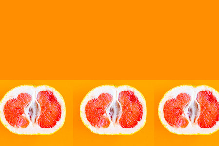 Sliced grapefruit pattern on bright orange background, minimal concept, copy space for the text,...