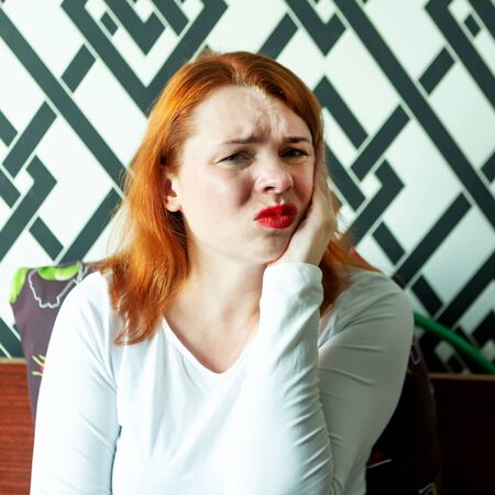 woman with toothache is sitting on the bed, closeupの写真素材