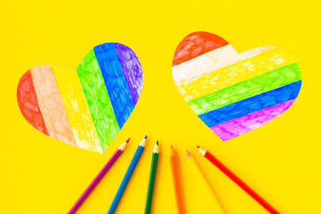 Hearts in lgbtq colors and pencils on bright yellow background, top viewの写真素材