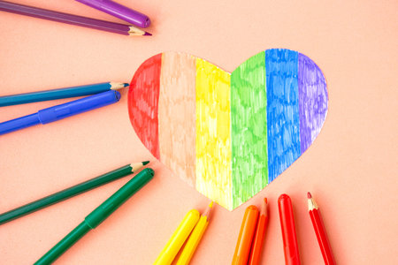 Heart in lgbtq colors and pencils on pastel pink background, top viewの写真素材