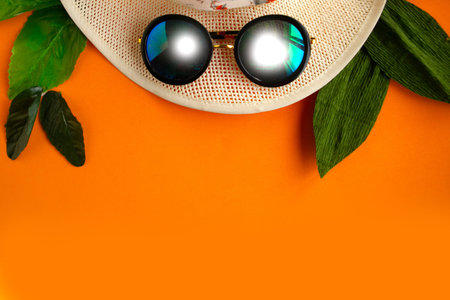 Straw hat and sunglasses on bright orange background, minimal concept, summer vacation concept, copy...