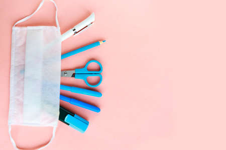 School supplies and medical mask on pastel pink background. Back to school concept. School quarantine concept. Top view, copy spaceの写真素材
