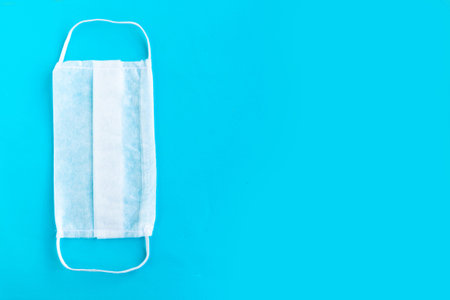 Medical mask on blue background, covid-19 concept, copy space