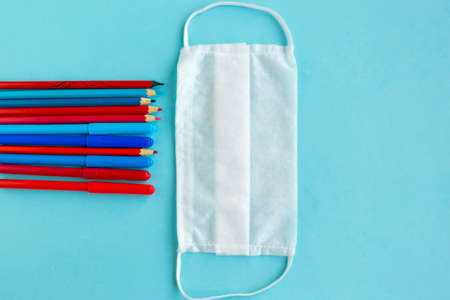 Color pencils and medical mask on blue background, top view. Back to school concept, school quarantine conceptの写真素材