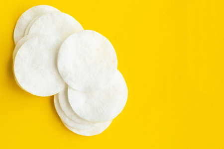 Cotton sponges on bright yellow background, top view
