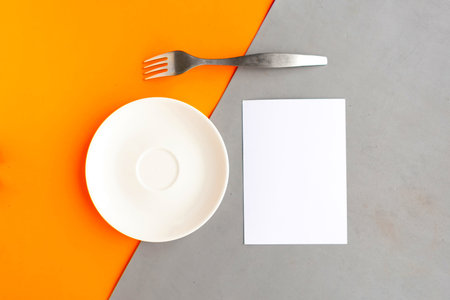 White mockup plate, blank and fork on orange and gray geometric background. Copy space for the text....