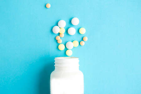 Pills in bottle on blue background, top viewの写真素材
