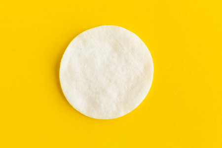 Cotton sponge on bright yellow background, top view