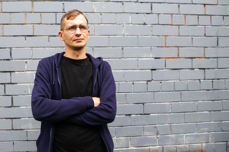 Portrait of young goodlooking man against gray brickwall. Lots of copyspace.