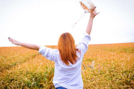 Ginger girl is running in a wheat field, summer backgroundの写真素材