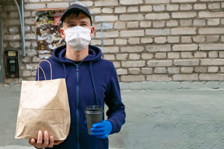Courier in protective mask delivers takeaway food. Coronavirus covid-19 pandemic conditions.の写真素材