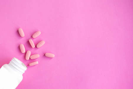 Pills in bottle on pink background, top view, copy spaceの写真素材