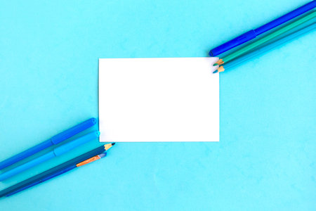 Color pencils and white mockup blank on blue background, top viewの写真素材