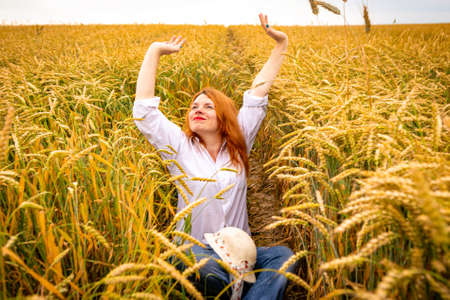 Redhead lady in wheat field, summer backgroundの写真素材