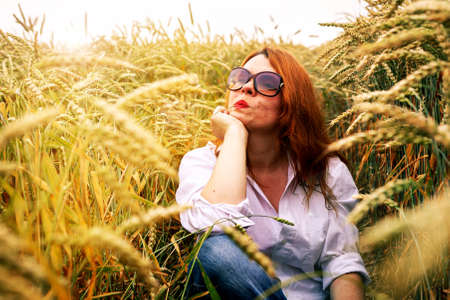 Redhead lady in wheat field, summer backgroundの写真素材