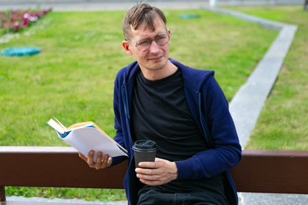 Young man is reading a book in the park, close up
