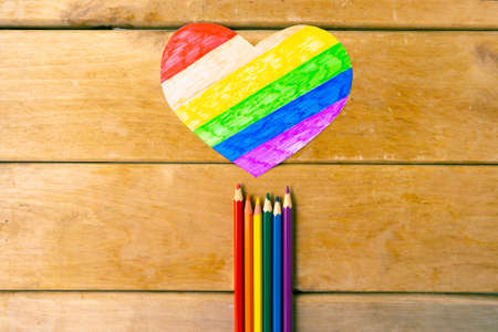 Pencils in lgbtq colors and heart on wooden background, top viewの写真素材