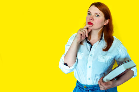 Redhead girl with books on yellow background. Back to school concept