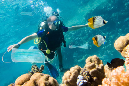 Diver and face masks under water. Environment pollution of surgical masks during the coronavrius