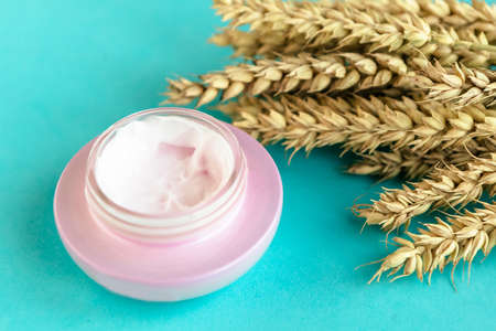 Wheat and barley natural cosmetic. Cosmetic jar and wheat ears on blue background.の写真素材