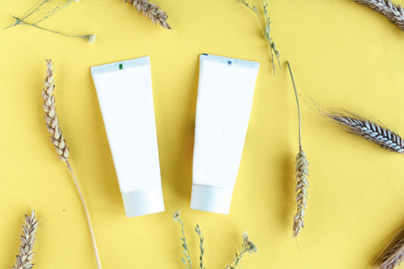 Wheat and barley natural cosmetic. Cosmetic tubes and wheat ears on yellow background.の写真素材