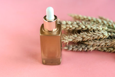 Wheat and barley natural cosmetic. Cosmetic bottle and wheat ears on pink background.の写真素材