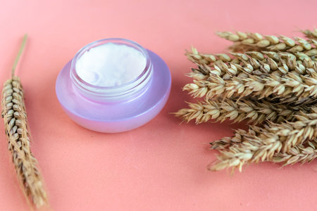Wheat and barley natural cosmetic. Cosmetic jar and wheat ears on pink background.の写真素材