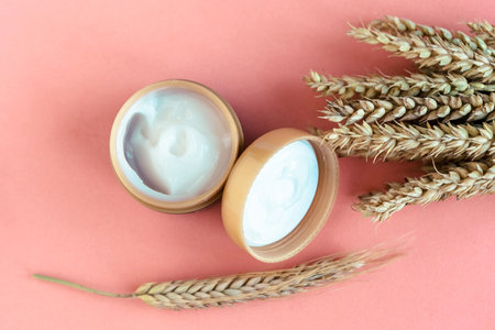 Wheat and barley natural cosmetic. Cosmetic jar and wheat ears on pink background.の写真素材