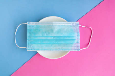 Singular mask on the plate, coronavirus concept, minimal concept, social distancing during the coronavirus pandemicの写真素材