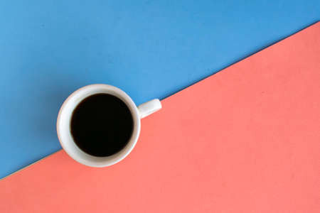 Coffee cup on geometric blue and pink background, top view, copy space for the text, minimal conceptの写真素材