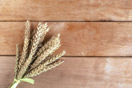 Bouquet of wheat ears on wooden background, top view, copy space for the textの写真素材