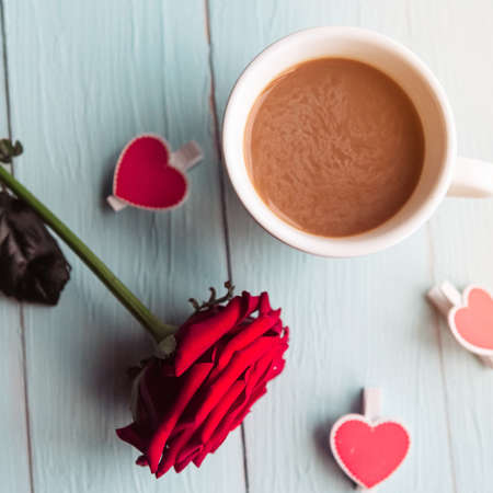 Red rose and coffee cup on wooden table, top viewの写真素材