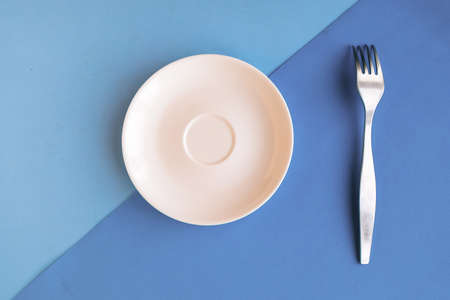 Empty plate and fork on gray and blue background. Copy space for the text. Minimal conceptの写真素材