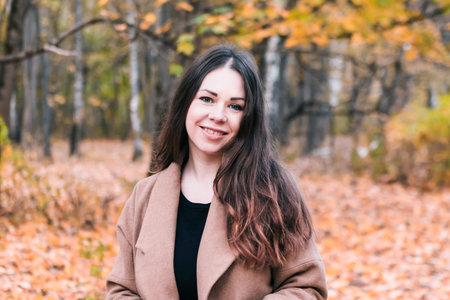 Portrait of young beautiful woman in autumn park, fall background