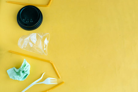 crumpled plastic disposable tableware on yellow background, top view