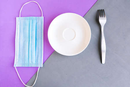 medical mask and empty plate on color background. Minimal concept. Covid-19 conceptの写真素材
