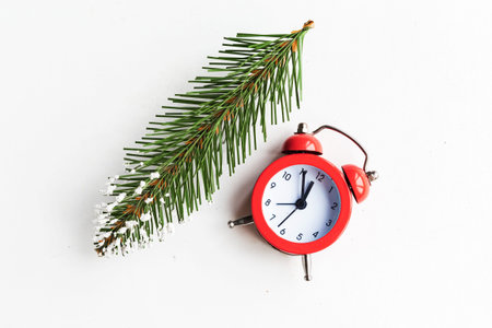 Fir branch and alarm clock on white. Christmas background. Minimal concept