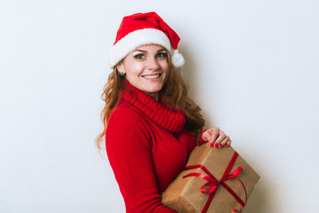 Portrait of young beautiful woman in Santa hat with gift box. Merry Christmas and Happy new year