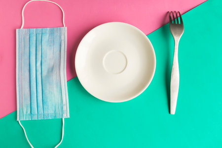 medical mask and empty plate on color background. Minimal concept. Covid-19 conceptの写真素材