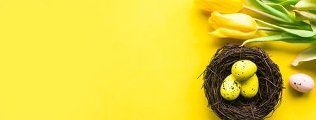 Easter eggs in a nest and bouquet of tulips on bright yellow background, copy space for the text. Beautiful Easter greeting cardの写真素材