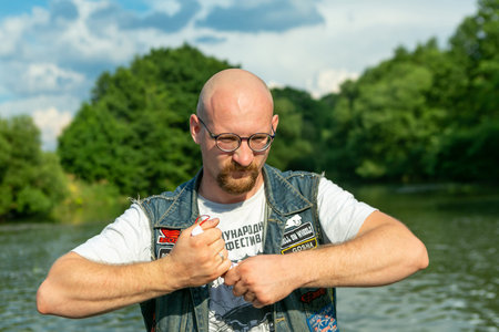 Minsk Belarus - August 27 2020: Young man is trying to tear up a medical facial mask during the coronavirus outbreakのeditorial素材