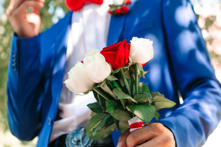 Groom with wedding bouquet. Man holds bouquet of red and white roses. Preparation for the weddingの写真素材