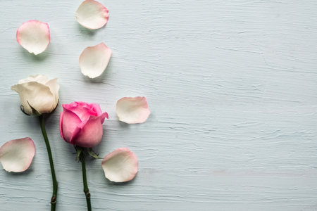 Two roses and petals on wooden background. Valentine's Day background. Copy space for the text